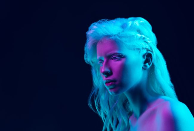 albino-girl-with-white-skin-natural-lips-white-hair-neon-light-isolated-black-studio-background